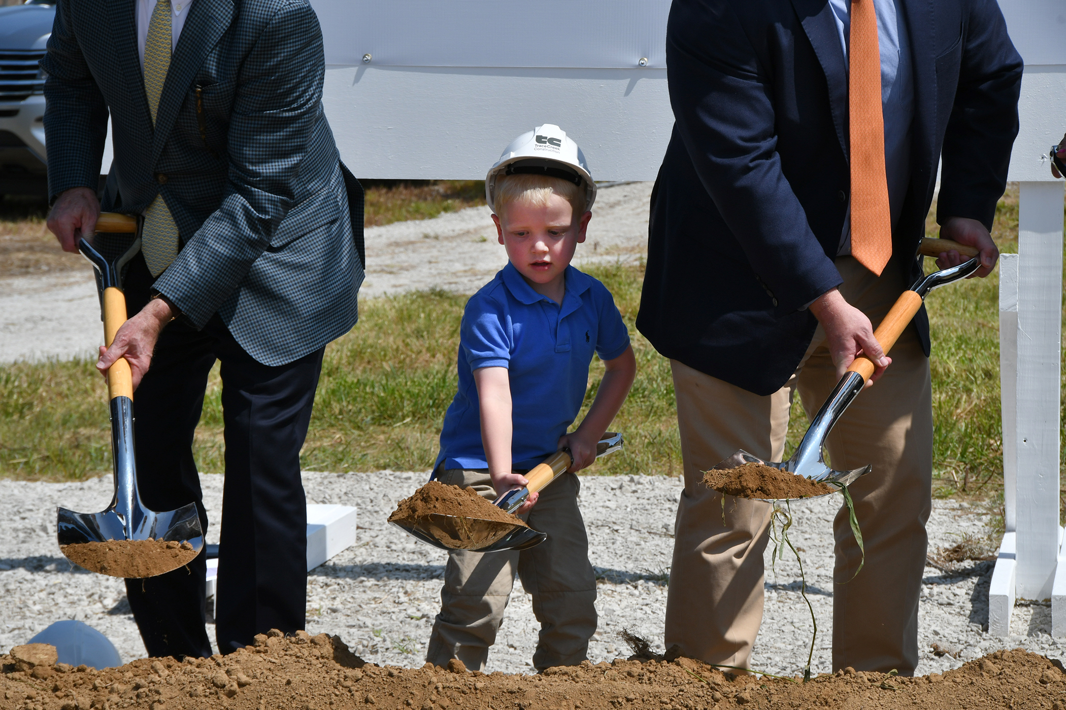 A little boy shoveling in between two men who are also shoveling.